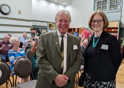 Brendan Moher and Consul General Janice McGann stand next to each other for a picture. In the background a small crowd gathering for the event chats excitedly.