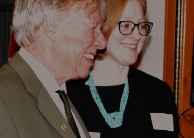 A candid photo of Brendan Moher (left) and Janice McGann (right) smiling as they converse with the crowd.