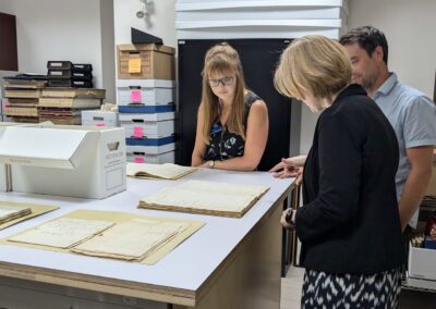 Staff members of the Peterborough Museum and Archives with Janice McGann gather around a table displaying documents from the emigration.