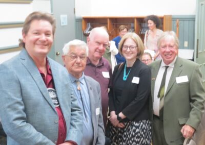 A group photo featuring from left to right: Chief Simpson of Alderville, Chief Knott of Curve Lake, Ken Armstrong, Janice McGann, and Brendan Moher. A small crowd in the background chats amongst themselves.